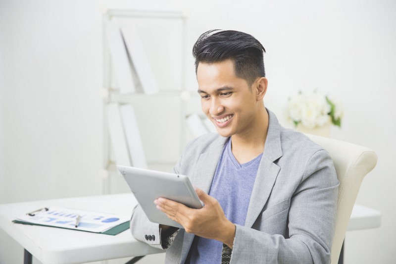 portrait of handsome asian businessman using tablet pc at his office